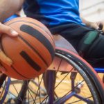 Basketball - Close-Up Shot of a Person Sitting on Wheelchair while Holding a Ball