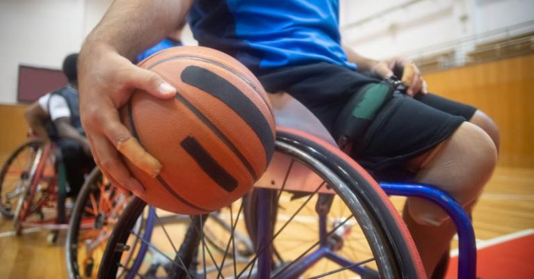 Basketball - Close-Up Shot of a Person Sitting on Wheelchair while Holding a Ball