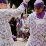 Traditional Dances - Two men in purple and white are holding a metal object