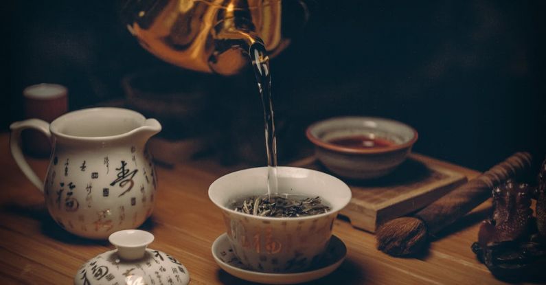 Tea Ceremony - Gold Kettle Pouring Hot Water on Cup of Tea