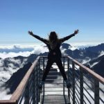 Origin Of Life - Person Standing on Hand Rails With Arms Wide Open Facing the Mountains and Clouds