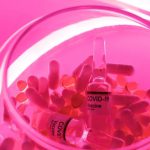 Medical Inventions - From above of glass bowl filled with pills and ampoules with vaccine for COVID 19 in pink bright neon light