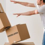 Difficult Languages - Full body of young man in sneakers and jeans pushing and falling boxes saying Work Problems Anxiety Stress and Deadline while fighting with problems