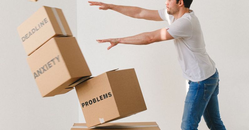 Difficult Languages - Full body of young man in sneakers and jeans pushing and falling boxes saying Work Problems Anxiety Stress and Deadline while fighting with problems