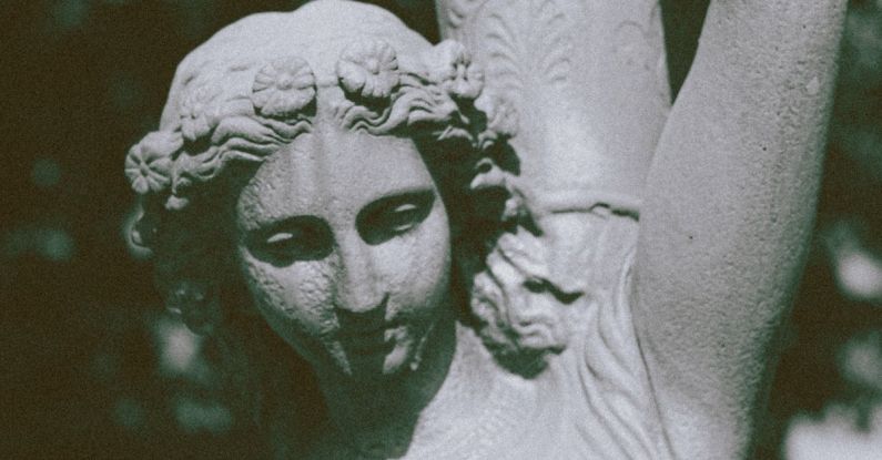 Celtic Mythology - Antique figure of young female in dress with hair tied up carrying vase on shoulders on blurred background