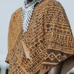 African Cultures - Anonymous ethnic male in mask and traditional apparel with ornament and accessories on meadow in town