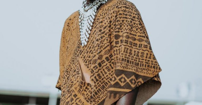 African Cultures - Anonymous ethnic male in mask and traditional apparel with ornament and accessories on meadow in town